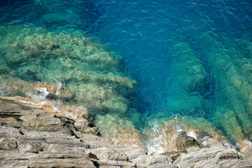 Rocky sea floor visible through crystal clear turqoise water of Mediterranean sea in Cinque Terre，Italy