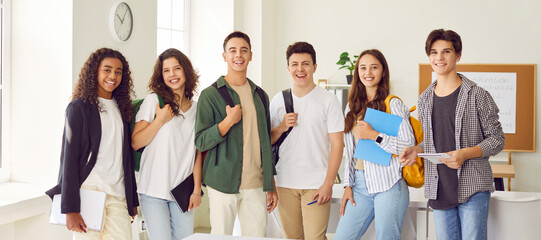 Portrait of a happy high school students group looking cheerful at camera and smiling standing in...