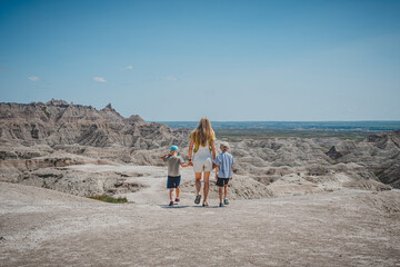Mother and sons walking along a ridge, looking out at the rock formations of Badlands National Park
