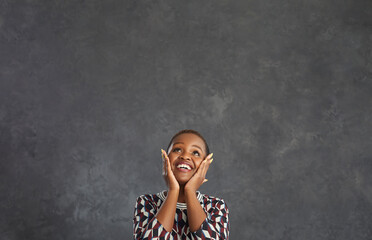 Overjoyed young African American woman isolated on black studio background triumph with amazing...