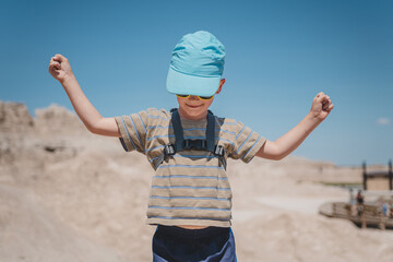 Young boy raising his hands amidst the rock formations of Badlands National Park