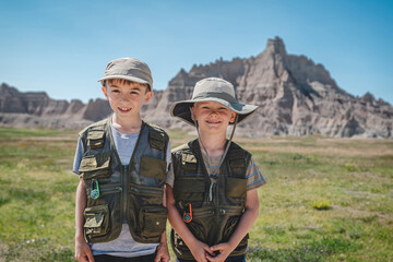 Two brothers wearing junior ranger vests in front of rock formations in Badlands National Park