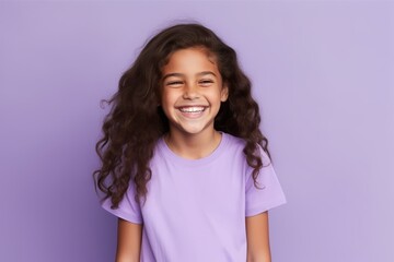 Portrait of smiling little girl with long curly hair on purple background