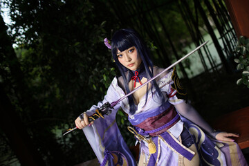 Portrait of a beautiful young woman game cosplay with samurai dress costume on Japanese garden