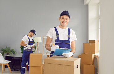 Young smiling mover man checking items list for moving, individual or company worker writing...