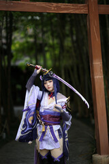 Portrait of a beautiful young woman game cosplay with samurai dress costume on Japanese garden