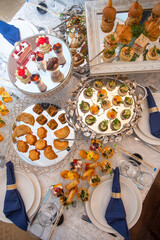 Elegant Catering Food Display with Variety of Appetizers and Desserts on White Tablecloths