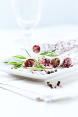 Sliced french salami with fresh rosemary and olives on white background. Copy space.
