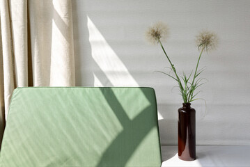 Minimal spring summer home decor, vase with dandelion flowers, green textile chair with natural aesthetic sun light shadows, beige linen curtain, aesthetic sustainable still life