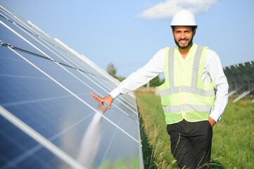 Portrait of Young indian male engineer standing near solar panels, with clear blue sky background, Renewable and clean energy. skill india, copy space.