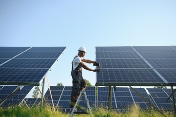African American engineer maintaining solar cell panels. Technician working outdoor on ecological...