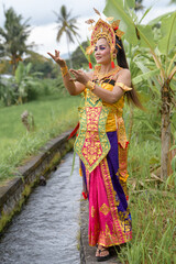 Beautiful bali portrait women in traditional costumes stands by a serene stream