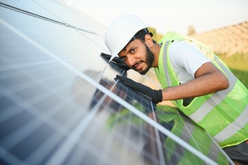 Indian man in uniform working near solar panel.