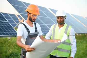 Multiracial team of engineers on solar panels. African american and arab engineer working on solar panel farm.