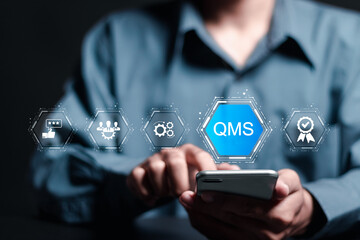 QMS, Quality management system concept. Businessman use smartphone with virtual QMS icon for management system defining the management relationships of the organization.