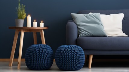 Cozy and stylish living room with dark blue sofa and knitted poufs in Scandinavian style
