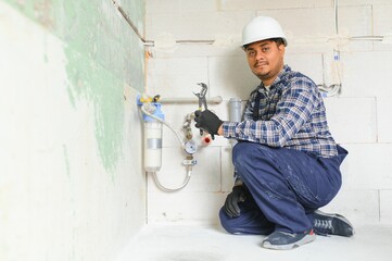 Indian plumber installing water equipment - meter, filter and pressure reducer