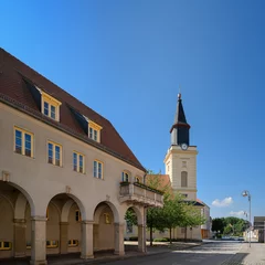 Foto op Canvas Das denkmalgeschützte Rathaus von Trebbin mit Säulengang und Balkon, dahinter die Stadtkirche "St. Marien" © ebenart