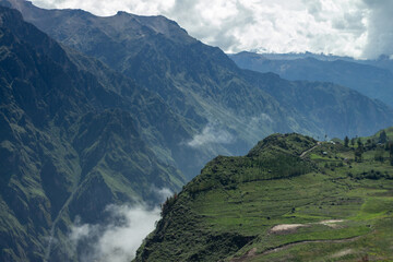 Fototapeta premium Spectacular and amazing colorful panorama of the Andes Mountains. Farmland near the Colca Canyon, Peru. Cloudy sky. Snow on the peaks, white clouds blue sky, green grass. Snowy mountain range.