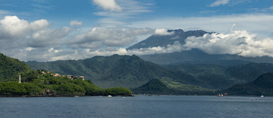 Scenic coastline, rolling hills and mount Agung volcano on a famous tropical Bali island in Padang Bai bay