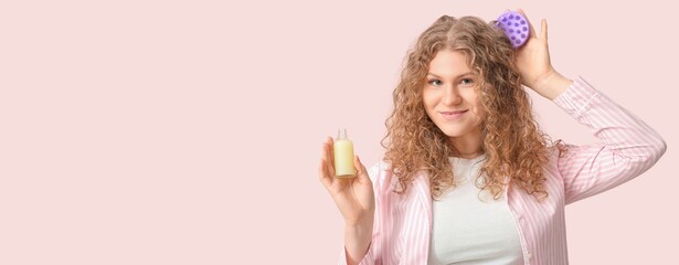 Beautiful young woman with hair scalp massager and cosmetic serum on pink background with space for text