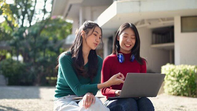 Group of confident Asian students wearing headphones, relaxing, studying in-depth information, talking, communicating, and seeking knowledge online. Administration of laptops at the university.