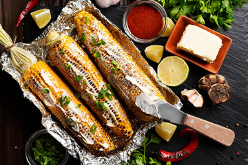 Grilled Sweetcorn with smoked paprika lime and butter in tin foil on kitchen table healthy gluten free flat lay food background