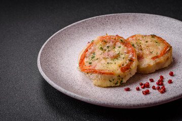 Delicious baked fish fillet with cheese, tomatoes, salt, spices and herbs