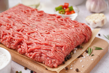 Wooden board of fresh minced meat with spices on white background