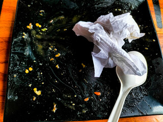 Empty food plate filled with used tissues and white plastic spoon. Selective focus.
