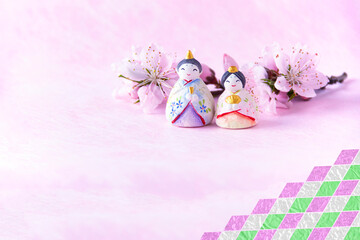 雛祭りのおひな様と桃の花（和紙のピンクバック・ピンク、緑、白のひし形の合成）