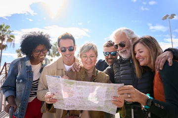 Fotobehang Group of diverse middle-aged tourist people standing looking at travel map in hands on street of vacation city happy and smiling on sunny day. Adults friends in community enjoying a trip together  © CarlosBarquero