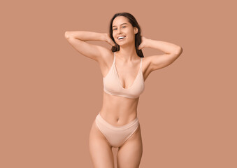 Beautiful young woman in nude underwear on beige background