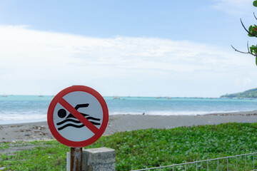 Sign, no Swimming on the Beach with a blurry beach as a background