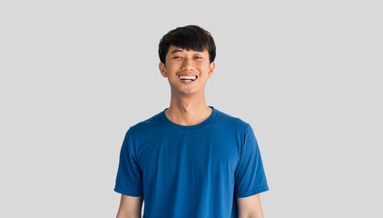 Young man in blue t-shirt smiling happily isolated on gray background.