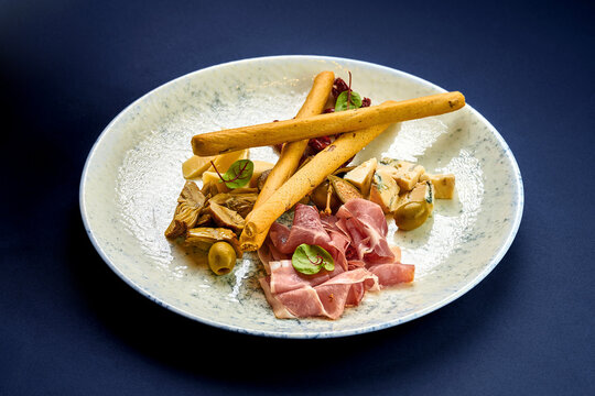A plate of antipasti, artichokes, cheese, grisini and jamon cr
