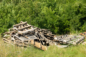 Heap of old wooden pallets, dump on the background of nature.
