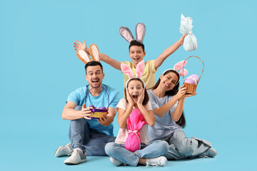 Happy family in bunny ears with Easter eggs sitting on blue background