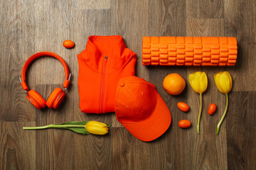 Sportswear and accessories, with flowers, on a wooden background.