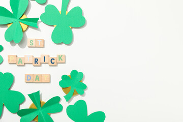 Paper clover leaves, golden coins and letters on white background, space for text