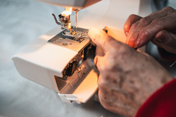 detail fingers of seamstress preparing sewing machine