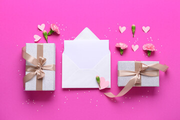Envelope with blank card, gift boxes and carnation flowers on pink background. International...