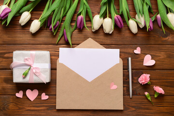 Envelope with blank card, gift box and tulip flowers on wooden background. International Women's Day celebration
