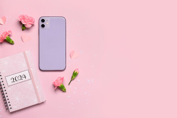 Composition with modern mobile phone, notebook and carnation flowers on pink background