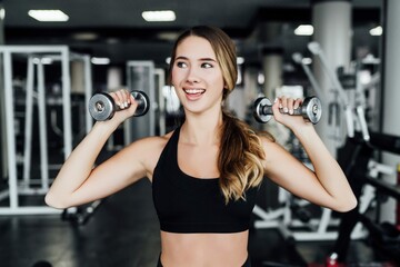 Fototapeta na wymiar Portrait Attractive Sports Girl With Dumbbells Her Hands Time Sports Workout Modern Gym