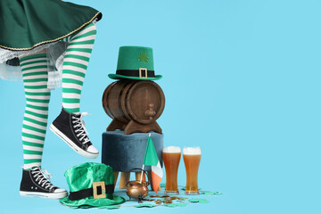 Female legs in green stockings with beer and decorations for St. Patrick's Day celebration on blue...