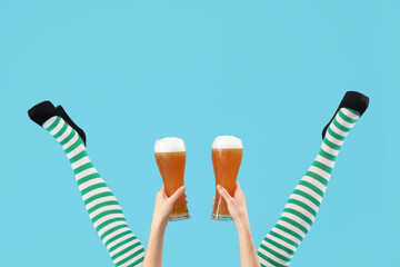 Female legs in green stockings with glasses of beer on blue background. St. Patrick's Day...