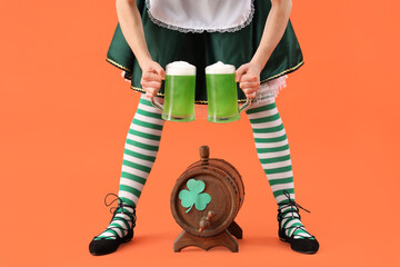Woman in waitress costume with barrel and glasses of beer on orange background. St. Patrick's Day...