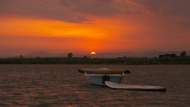 Surfing boat against colorful sky. A view of surfing wooden boat on waves during nightfall time in summer.