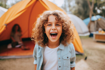 Happy boy laughing at camera next to camping tent